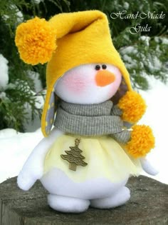 a stuffed snowman wearing a yellow hat and scarf on top of a tree stump