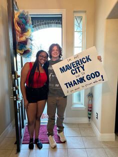 two women standing in front of a door holding a sign that says merrick city thank god