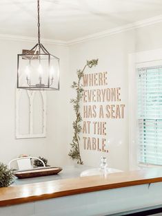 there is a light hanging from the ceiling in this kitchen with white walls and wood countertops