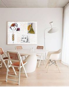 a dining room table with chairs and a painting on the wall in front of it