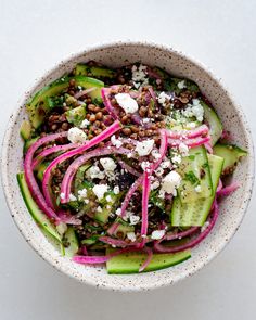 a white bowl filled with cucumber, radishes and feta cheese