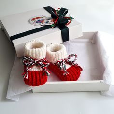 a pair of red knitted baby booties sitting on top of a white box