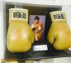 two yellow boxing gloves with signed pictures on them in a display case at a store