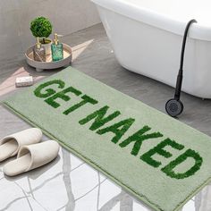 a bathroom rug that says get naked on the floor next to slippers and a bathtub