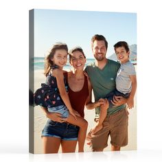 a family is posing for a photo on the beach with their child in front of them