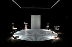 an empty room with several chairs and lights on the floor in front of a door