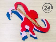 a red and blue lizard with a ruler in it's mouth sitting on a table