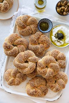 several bagels on a tray with dipping sauces and nuts in bowls around them