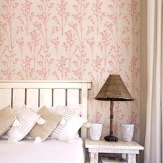 a white bed sitting next to a lamp on top of a table