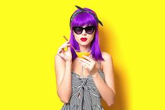 a woman with purple hair and sunglasses is holding a yellow object in her hands while wearing black glasses