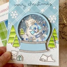 someone is holding up a christmas card with a bear in the snow globe on it