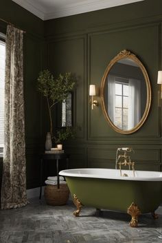 a green bathroom with an oval mirror and claw foot bathtub in the center, along with two lamps on either side of the tub