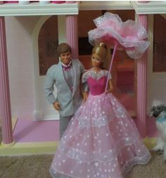 a barbie doll and man standing in front of a toy house with a dog on the floor