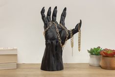 a black hand with chains on it and a potted plant in the corner next to it