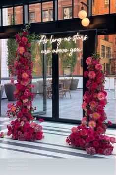 two tall pink flowers are on display in front of the entrance to an office building