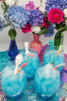 three blue glasses with toothbrushes in them on a table