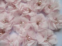 pink flowers and pearls are arranged on a white surface