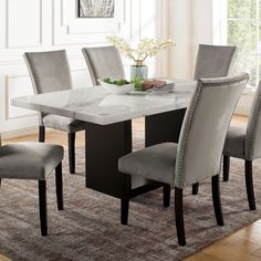 a dining room table with grey chairs and a white marble topped centerpiece in the middle