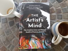 a book and two mugs sitting on a stone table with the title, the artist's mind