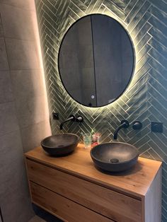 two black sinks sitting on top of a wooden counter next to a wall mounted mirror