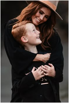 a woman hugging a young boy who is wearing a cowboy hat and black coat with his arms around him