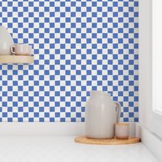 a blue and white checkered wallpaper in a kitchen with two vases on the counter