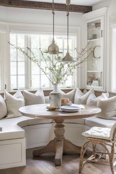 a corner table in the middle of a living room with white couches and pillows