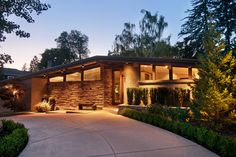 a house with lights on in the front yard and driveway leading to it's entrance