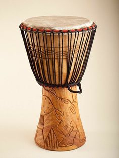 a wooden drum with metal strings and an animal design on the top, sitting in front of a white background