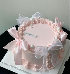 a pink cake decorated with bows and pearls