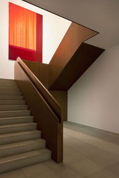 a staircase leading up to a red painting on the wall behind it in an empty room