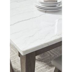 a white marble dining table with two chairs and plates on the table in front of it