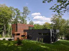 a modern house in the woods surrounded by trees and grass, with large windows on each side