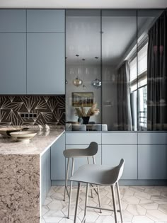 a modern kitchen with blue cabinets and marble counter tops, along with a dining room table