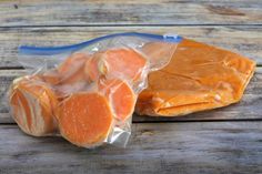 two pieces of meat wrapped in plastic sitting on a wooden table