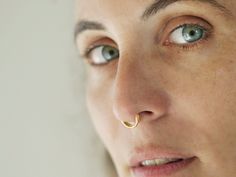 a close up of a woman's nose with a gold nose ring on it