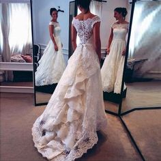 a woman in a wedding dress looking at herself in the mirror and taking her own picture