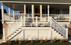 a white house with stairs leading up to the front door and second story porch area