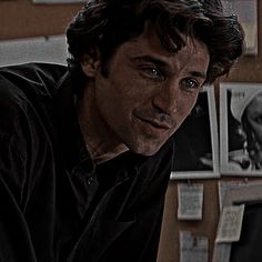 a man is staring at the camera while sitting in front of a desk with papers on it