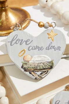 a wooden heart shaped ornament that says, love came down on the beach