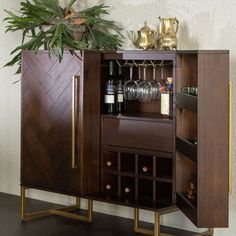 a wooden cabinet with wine glasses and bottles in it next to a potted plant