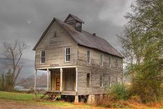 an old wooden house sitting on top of a lush green field