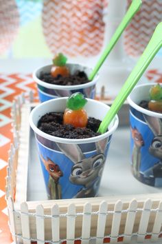 two cups filled with pudding and gummy bears on top of a tray next to other desserts