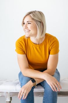 a woman sitting on top of a bench with her arms crossed and looking off to the side