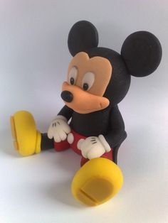 a mickey mouse figurine sitting on top of a white table next to a yellow object