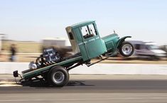 an old green truck driving down the road