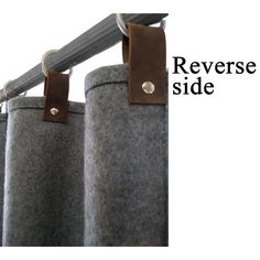 a pair of gray curtains with leather straps hanging from the top and bottom of them