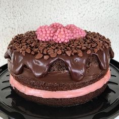 a chocolate cake with pink frosting and chocolate sprinkles on the top