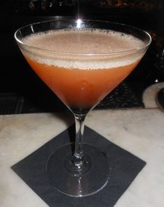 a glass filled with liquid sitting on top of a table next to a black napkin