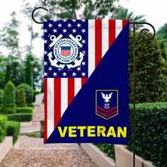 an american flag with the words veteran on it hanging from a pole in front of a garden